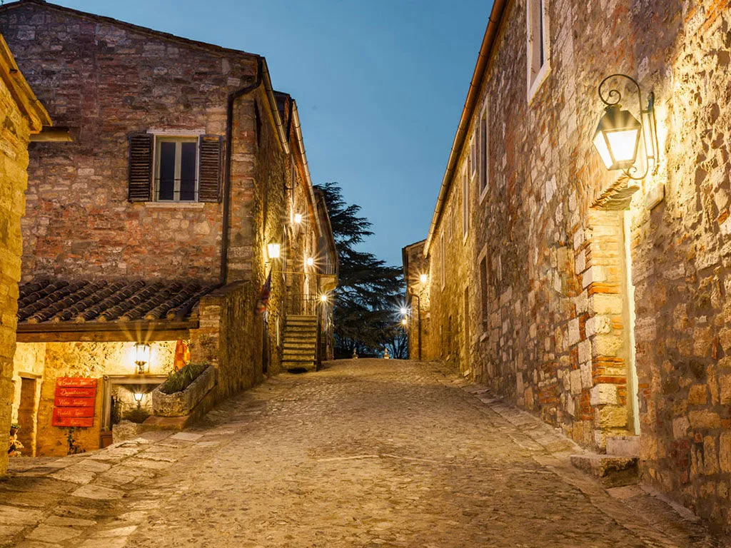 The borgo's cobblestone lane at dusk